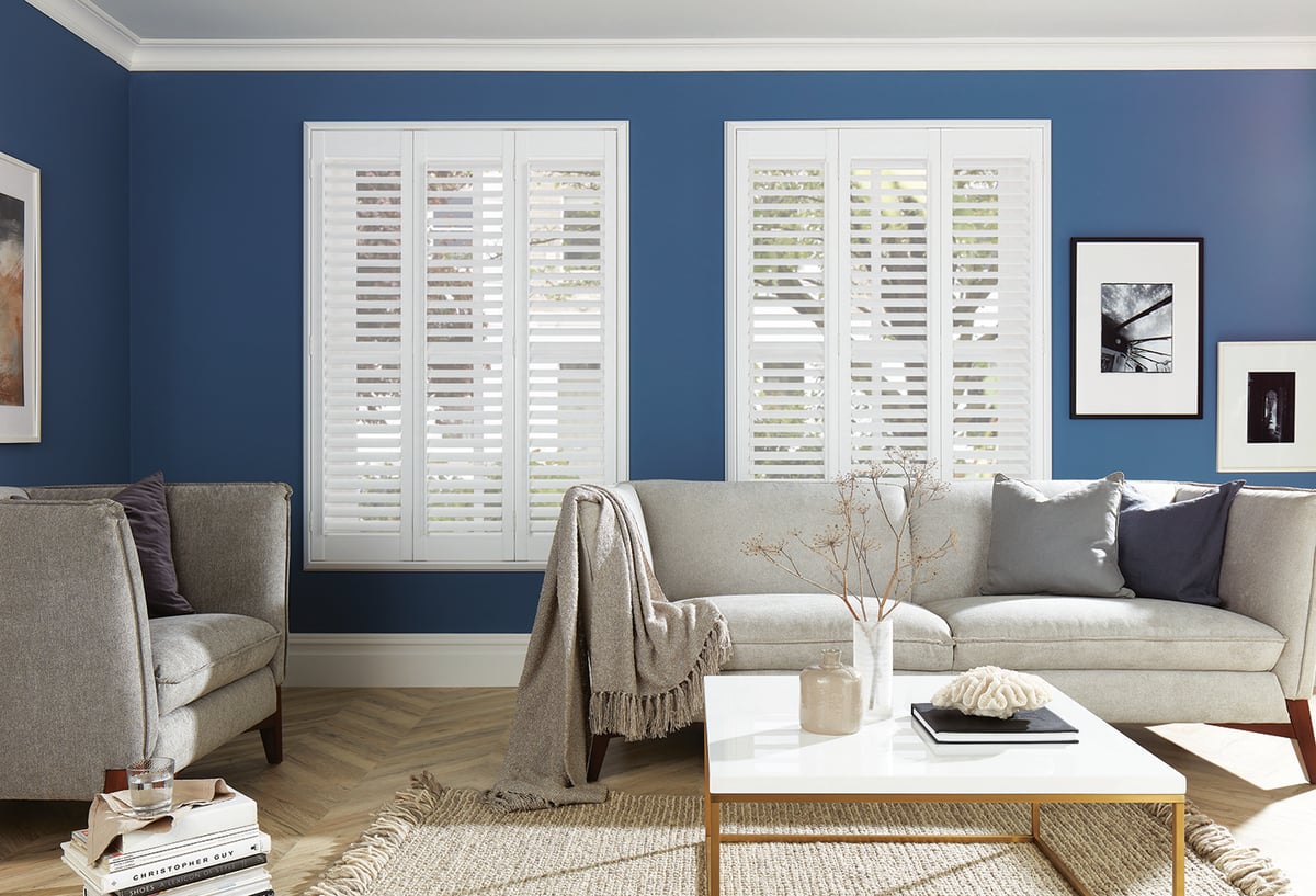 Full height shutters on windows in a blue lounge